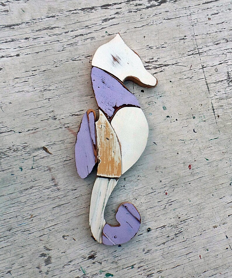 May include: A purple, white, and beige wooden seahorse sculpture. The seahorse is made of reclaimed wood and has a rustic, distressed look.