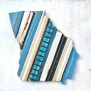 May include: A blue, white, and teal wood wall art piece shaped like the state of South Carolina. The piece is made of various pieces of wood, each with a different texture and color.