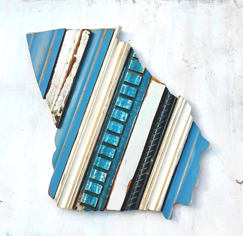 May include: A blue, white, and teal wood wall art piece shaped like the state of South Carolina. The piece is made of various pieces of wood, each with a different texture and color.
