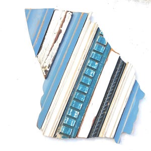 May include: A blue, white, and teal wood wall art piece in the shape of the state of Georgia. The wood is arranged in a diagonal pattern, creating a unique and modern look.