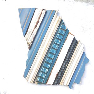 May include: A blue, white, and teal wood wall art piece in the shape of a state. The wood is arranged in a diagonal pattern.