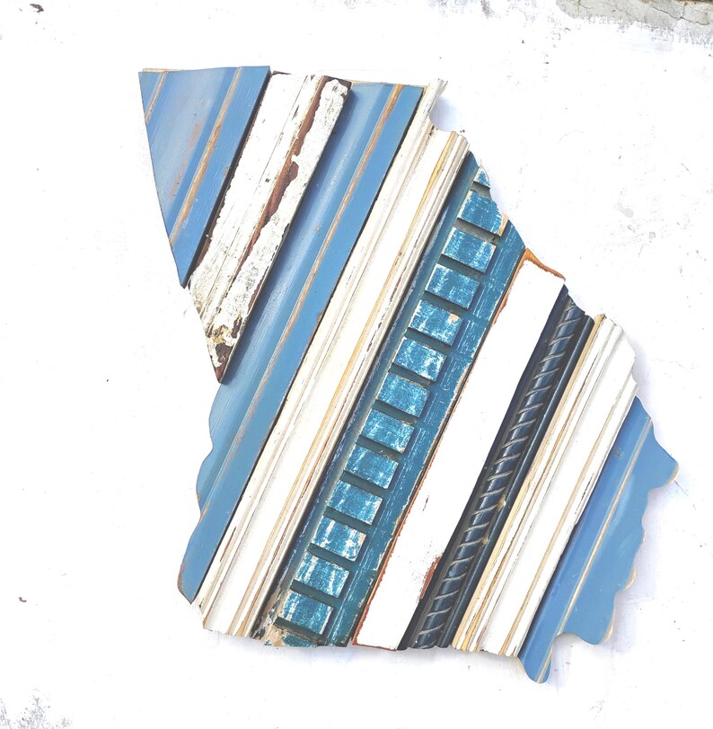 May include: A blue, white, and teal wood wall art piece in the shape of a state. The wood is arranged in a diagonal pattern.