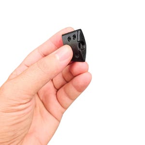May include: A black plastic cable management clip with a rectangular shape and a small hole on one side.