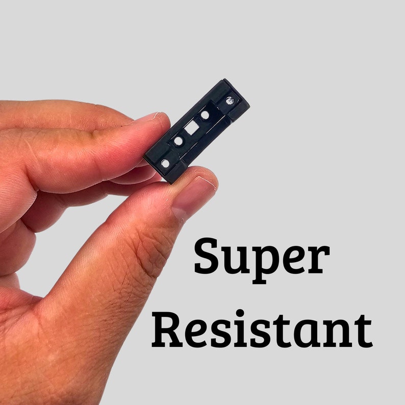 May include: A small, black plastic component with multiple holes and a rectangular opening. The text "Super Resistant" is displayed in bold, black letters against a light gray background.