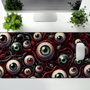 May include: A rectangular mousepad featuring a detailed, surreal design of numerous eyeballs in various sizes and colors, connected by red veins. The mousepad has a white mouse on the right side. The overall theme is horror or fantasy.