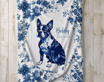 May include: White blanket with a blue floral design border and a central image of a Boston Terrier dog. The dog is in a sitting position, with the name "Bobby" and the years "2012-2025" printed on the blanket.