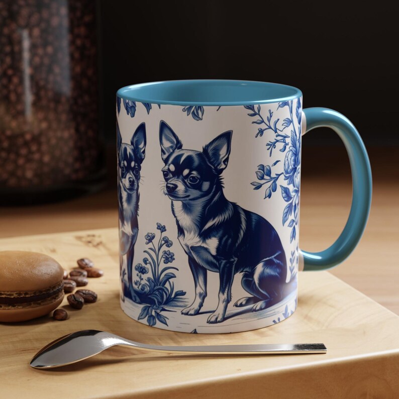 May include: A ceramic mug with a blue interior and handle, featuring a blue and white illustration of a Chihuahua dog. The mug has a floral design and is set on a wooden surface.