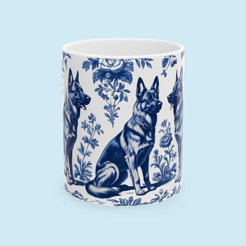 May include: A white ceramic mug with a blue and white pattern of German Shepherd dogs and floral designs. The dogs are in a sitting position and the flowers are in a variety of styles.