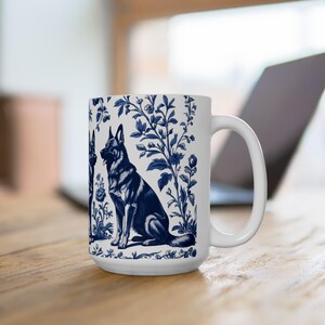 May include: White ceramic mug with a blue and white design featuring German Shepherd dogs in a floral pattern.
