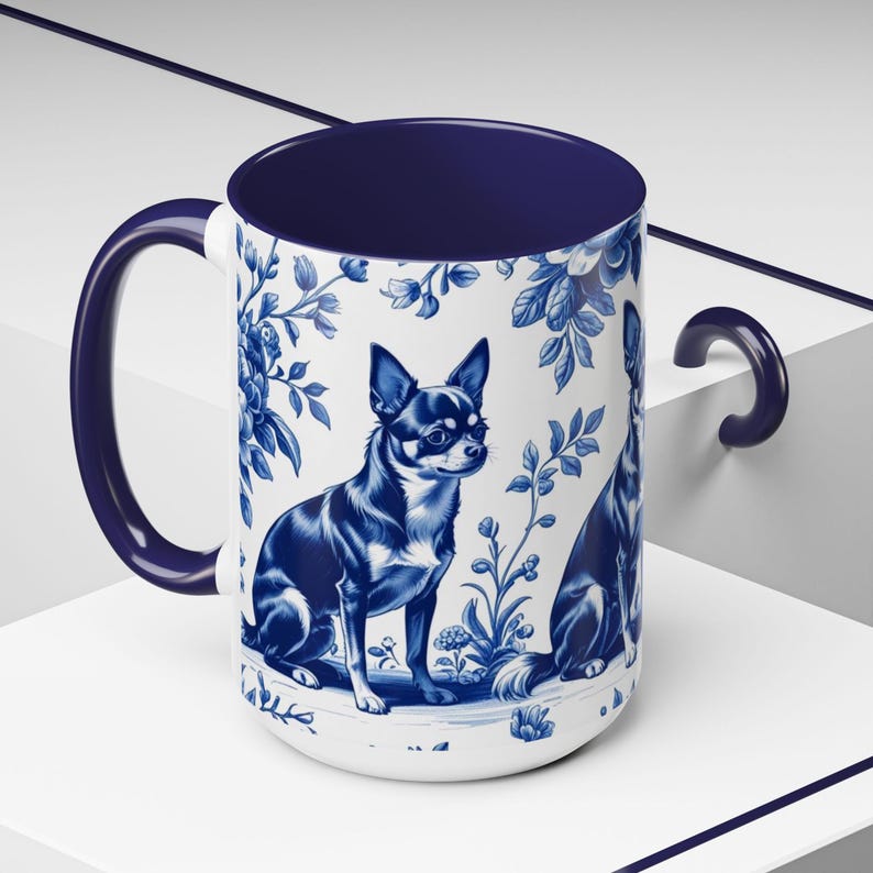 May include: White ceramic mug with a blue interior and handle. The mug features a blue and white floral design with two illustrations of a Chihuahua dog. The dog illustrations are in a blue and white colour scheme.