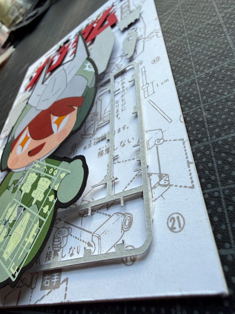 May include: A partially assembled model kit featuring a cartoon character with red and green accents. The kit includes a sprue of plastic parts and a printed instruction sheet with Japanese text and diagrams. A 1 cm ruler is visible.