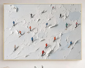 Puede incluir: Pintura abstracta texturizada en blanco y azul claro que representa esquiadores en una montaña nevada. Los esquiadores visten chaquetas de colores, incluyendo rojo, azul y verde. La obra está enmarcada en un marco dorado.