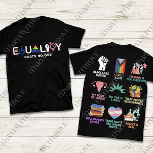 Op de afbeelding: Twee zwarte t-shirts met grafische ontwerpen. Eén shirt zegt "EQUALITY HURTS NO ONE" met LGBTQ+-symbolen. Het andere shirt toont verschillende slogans voor sociale rechtvaardigheid, waaronder "Black Lives Matter" en "Love is Love."
