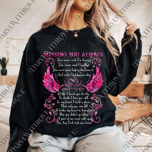 May include: Black sweatshirt with the text "MISSING YOU ALWAYS" in pink, along with a poem and pink angel wings design. The sweatshirt is a casual style, suitable for everyday wear.