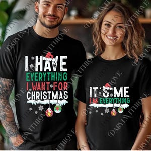 May include: Black t-shirts with Christmas-themed text. One shirt reads "I HAVE EVERYTHING I WANT FOR CHRISTMAS" with Santa hat and ornament graphics. The other says "IT'S ME I'M EVERYTHING" with similar graphics.