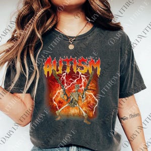 May include: Dark gray t-shirt featuring the word "AUTISM" in a fiery font above a skeleton holding two crossed swords. The design includes lightning bolts and a red and orange background.
