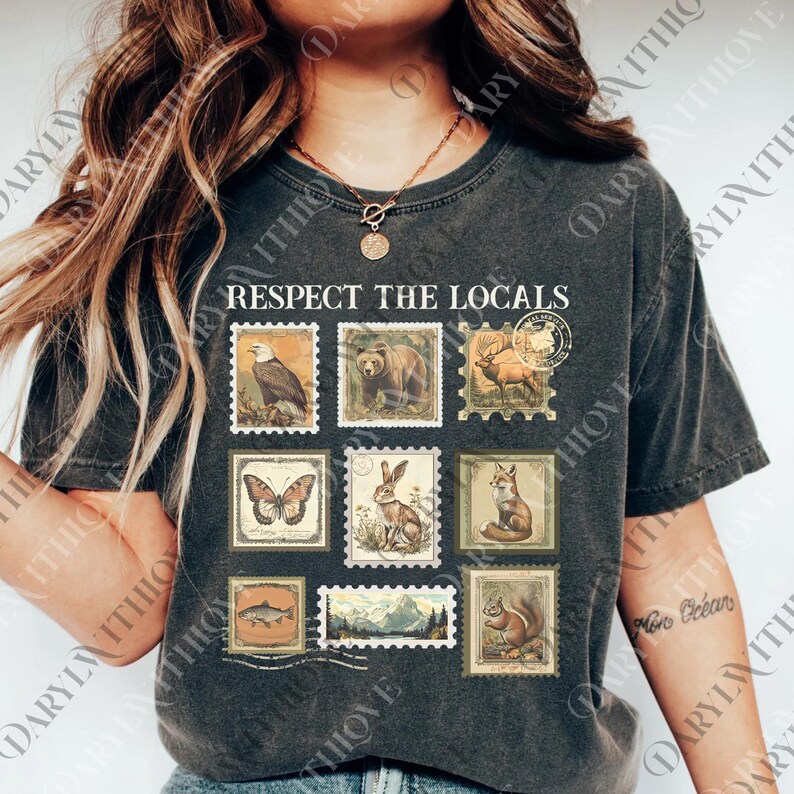 A woman wearing a black t-shirt with a graphic design of postage stamps featuring various animals, including a bear, eagle, and deer.