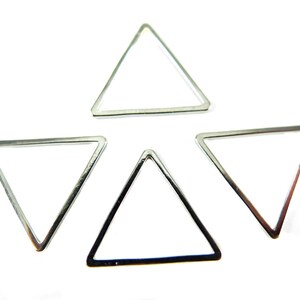 Puede incluir: Cuatro aros de metal de forma triangular plateados. Los aros son todos del mismo tamaño y forma, y están dispuestos en forma de estrella.