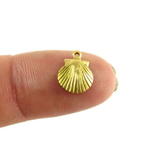 May include: A gold-colored seashell charm with a loop for attaching to a necklace or bracelet.