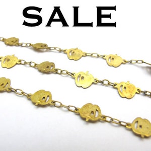 May include: Gold-toned metal chains with apple-shaped charms. The charms are evenly spaced along the chains, and the word "SALE" is displayed in large, bold black letters at the top of the image. The chains are arranged diagonally against a white background.