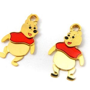 May include: Two gold-colored Winnie the Pooh charms with red shirts. The charms are perfect for adding a touch of Disney magic to jewelry or crafts.