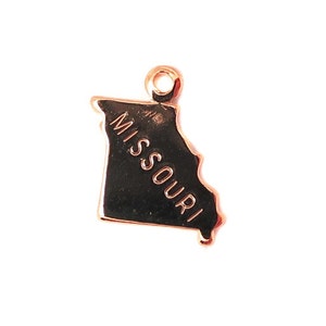 Könnte beinhalten: Goldfarbener Metallanhänger in Form des Bundesstaates Missouri mit der Aufschrift "MISSOURI".