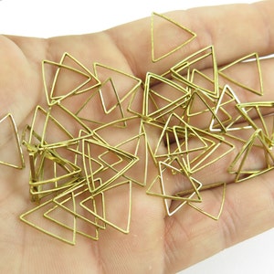Puede incluir: Un montón de formas triangulares de metal dorado, probablemente para la fabricación de joyas.