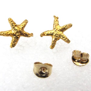 May include: A pair of gold-tone starfish stud earrings. The earrings are made of metal and have a textured finish.