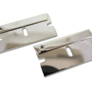 May include: Two silver-coloured razor blades with a hole in the centre. The blades are sharp and have a slightly curved shape.