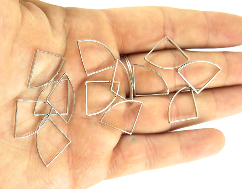 May include: Silver-toned metal geometric charms in various shapes, including triangles, squares, and curved segments. The charms are small and delicate, suitable for jewelry making or craft projects.