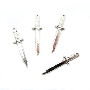 May include: Four silver-toned knife charms, each with a different design. The charms are small and delicate, perfect for adding a touch of whimsy to jewelry or crafts.