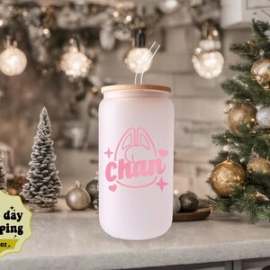 May include: A frosted glass water bottle with a bamboo lid and a pink bunny graphic with the name "Chan" on it. The bottle is 16 ounces.