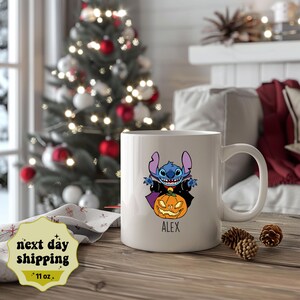 May include: White ceramic mug with a blue Stitch character dressed as a vampire holding a jack-o'-lantern. The mug has the name "Alex" printed on the bottom.