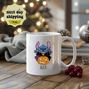 May include: White ceramic mug with a blue Stitch character dressed as a vampire holding a jack-o'-lantern. The mug has the name "ALEX" printed on the bottom.
