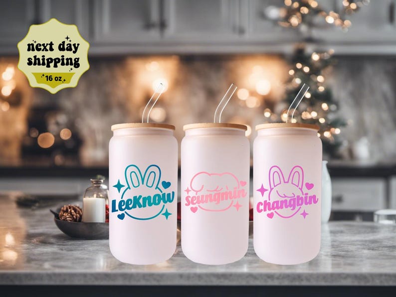May include: Three 16 oz. reusable tumblers with lids and straws. Each tumbler features a different pink and white cartoon bunny with a name underneath: Lee Know, Seungmin, and Changbin.