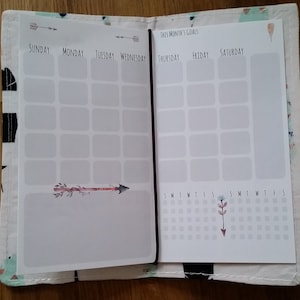 Puede incluir: Una agenda blanca con un diseño floral y el texto "Objetivos de este mes". La agenda tiene un calendario semanal con los días de la semana etiquetados del domingo al sábado. La agenda también tiene una sección para tareas diarias y un calendario mensual.