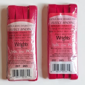 May include: Two packages of bright pink extra wide double fold fleece binding by Wrights. Each package contains 3 yards of 0.5 inch wide 100% polyester binding. The labels feature the text Extra Wide Double Fold Fleece Binding, Wrights, and a barcode.