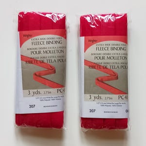 May include: Two packages of bright red extra wide double fold fleece binding by Wrights. Each package contains 3 yards of 1/2 inch wide 100% polyester binding. The labels feature the text "Wrights Extra Wide Double Fold Fleece Binding".