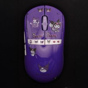 May include: Purple wireless computer mouse with Kuromi character graphics. The mouse features a scroll wheel and the word "Cutie" printed on the top. The bottom of the mouse has the word "Kuromi" printed on it.