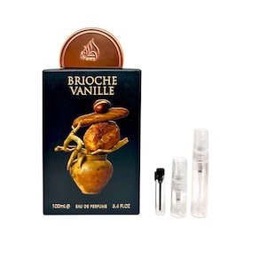 May include: A black perfume box with the words "BRIOCHE VANILLE" in gold lettering. The box features a gold illustration of a brioche and a small pot. The box is accompanied by three small perfume spray bottles and a vial. The box reads "100ml e Eau de Parfum 3.4 FL.OZ."
