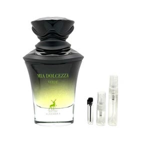 May include: A perfume bottle with a black cap and a green-yellow gradient. The bottle is labeled "MIA DOLCEZZA VERDE" with a deer logo and "MAISON ALHAMBRA" text. Several small sample vials are next to the bottle.