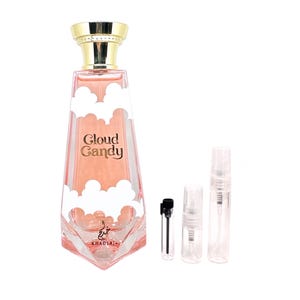 May include: A pink and gold bottle of Cloud Candy perfume by Khadlaj. The bottle is shaped like a cloud and has a gold cap. There are three small sample bottles of perfume next to the larger bottle.