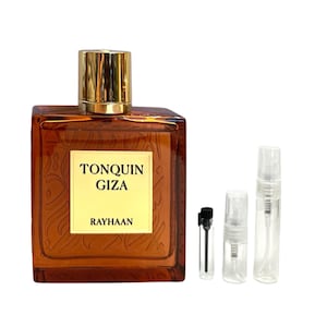 May include: A rectangular amber-colored perfume bottle with a gold cap, labeled "TONQUIN GIZA" and "RAYHAAN". Several small, clear sample vials are next to the bottle, suggesting a fragrance product.