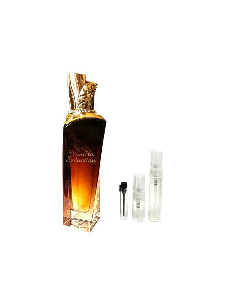 Pu&ograve; includere: Un flacone di profumo con un tappo dorato e ornato e un corpo sfumato dal marrone al giallo. Le parole "Vanilla Seduction" sono stampate sul davanti. Tre piccoli flaconi campione e un contagocce sono accanto al flacone di profumo.