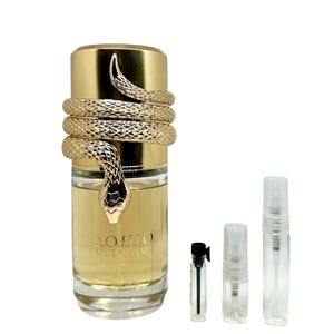 May include: A gold-colored perfume bottle with a snake wrapped around it, and the word "Musaam" in Arabic script. The bottle is accompanied by three small sample vials. The perfume bottle has a gold cap.