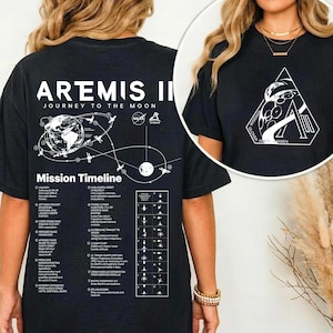 May include: Black t-shirt with white text and graphics. The back of the shirt features the words "Artemis II Journey to the Moon" above a mission timeline graphic. The front of the shirt has a white geometric design with the text "NASA".