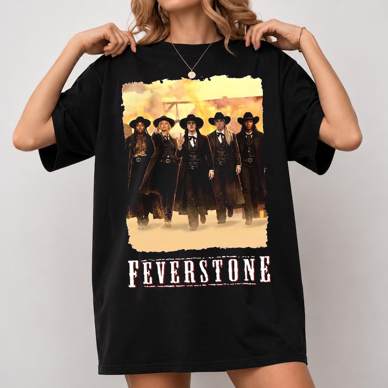 May include: A black short-sleeve t-shirt featuring a graphic print of five individuals in western-style attire, including long coats and cowboy hats, standing in a dusty landscape. The word FEVERSTONE is printed in white below the graphic.