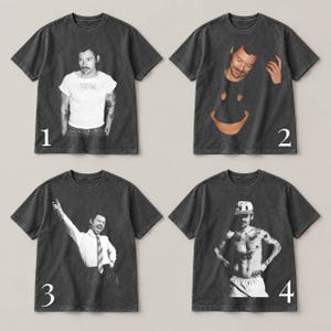 May include: Four charcoal gray short-sleeve t-shirts featuring different photographic prints of a man. Shirt 1 shows a man in a white t-shirt. Shirt 2 features a man's face above a large orange smiley face. Shirt 3 shows a man in a dress shirt and tie. Shirt 4 shows a shirtless man wearing a baseball cap.