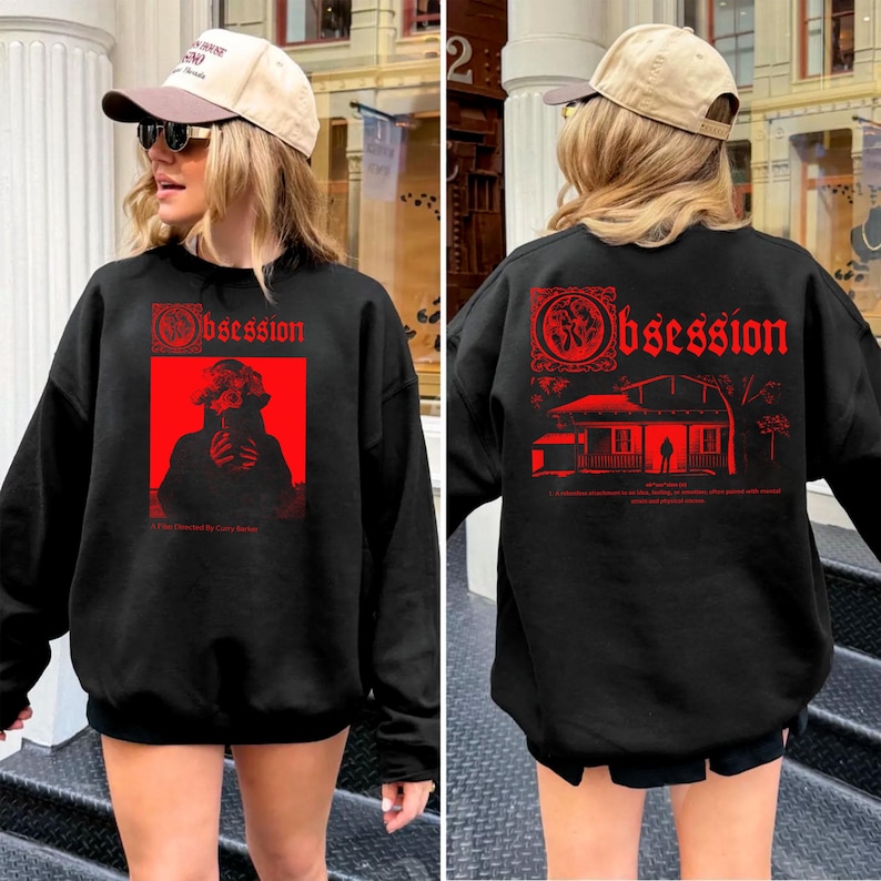 Op de afbeelding: Zwarte sweatshirt met rode grafische tekst en afbeeldingen. De voorkant heeft een rode rechthoek met een silhouet en het woord "Obsession". De achterkant heeft het woord "Obsession" en een huisafbeelding. De sweatshirt wordt door een persoon gedragen.