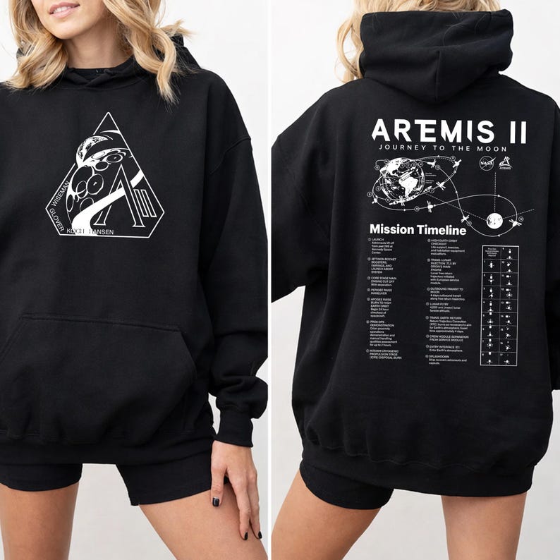 May include: Black hooded sweatshirt with a front graphic featuring a stylized astronaut and the text "Wiseman, Glover, Koch, Hansen". The back of the sweatshirt displays "Artemis II Journey to the Moon" with a mission timeline graphic.